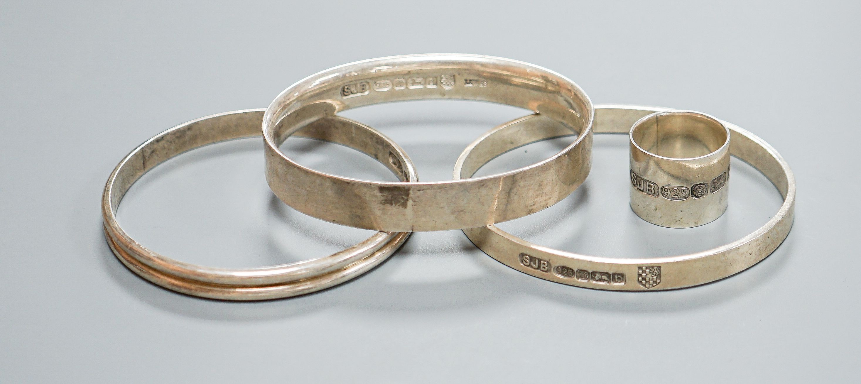 Three modern silver bangles and a large silver band, all by Simon J. Beer of Lewes